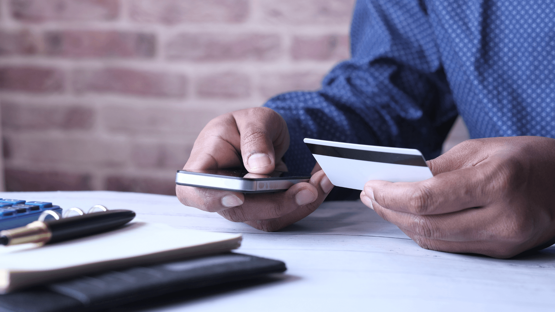 Man using iPhone with Credit Card in Hand