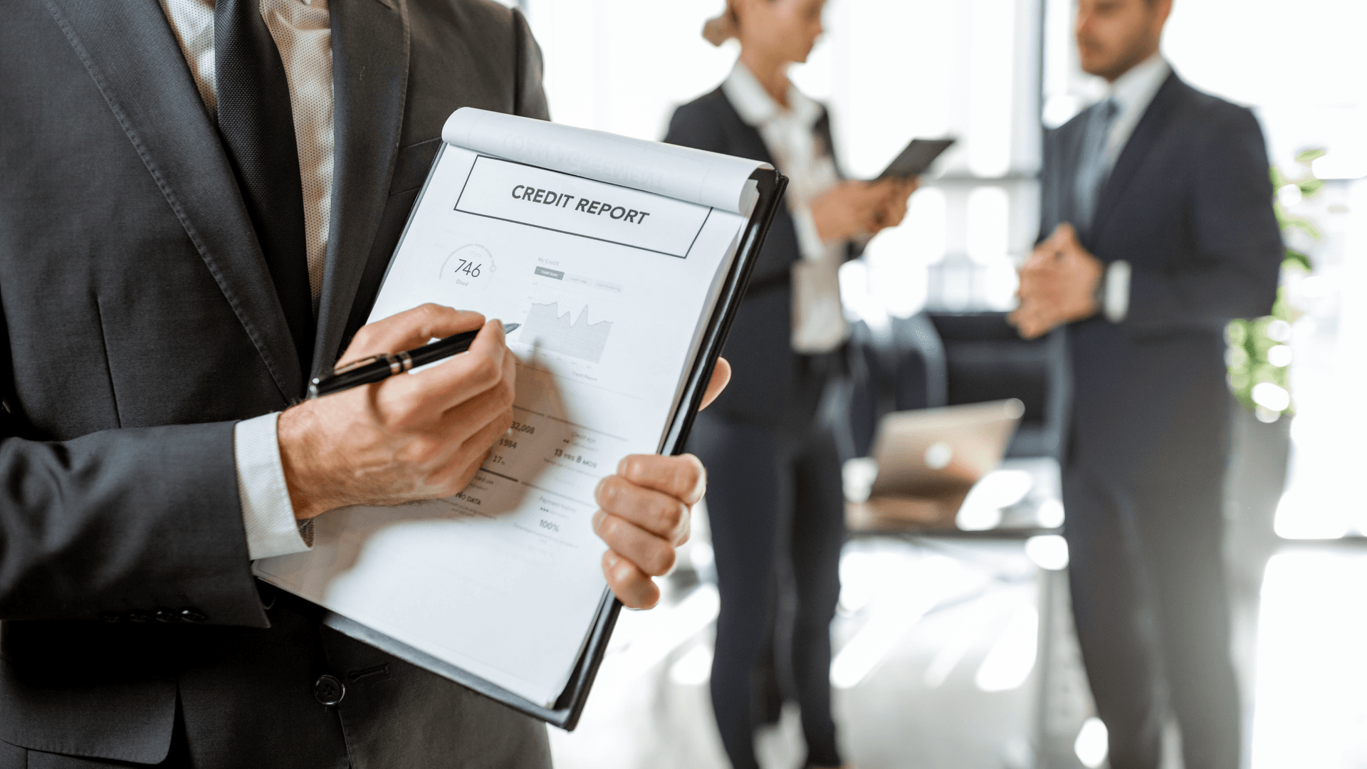 clip board with credit report, three business people in the background