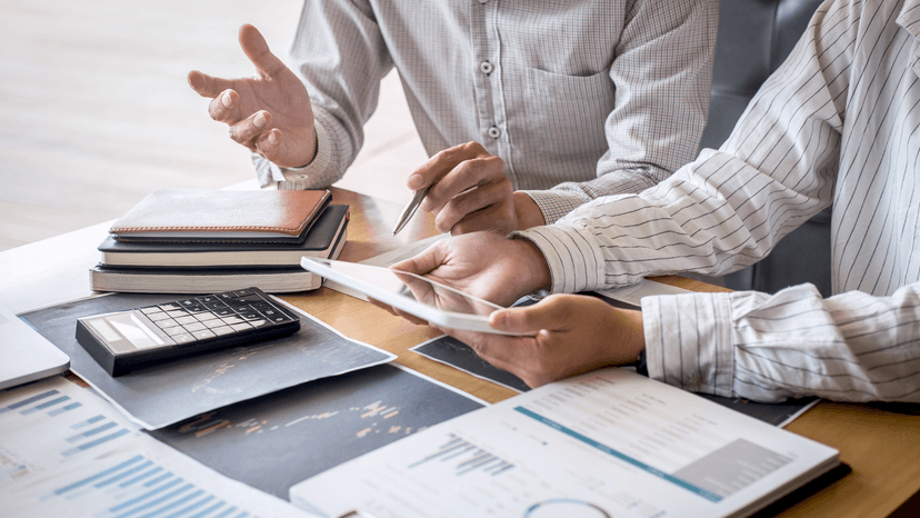The hands of two business professionals while looking at reports