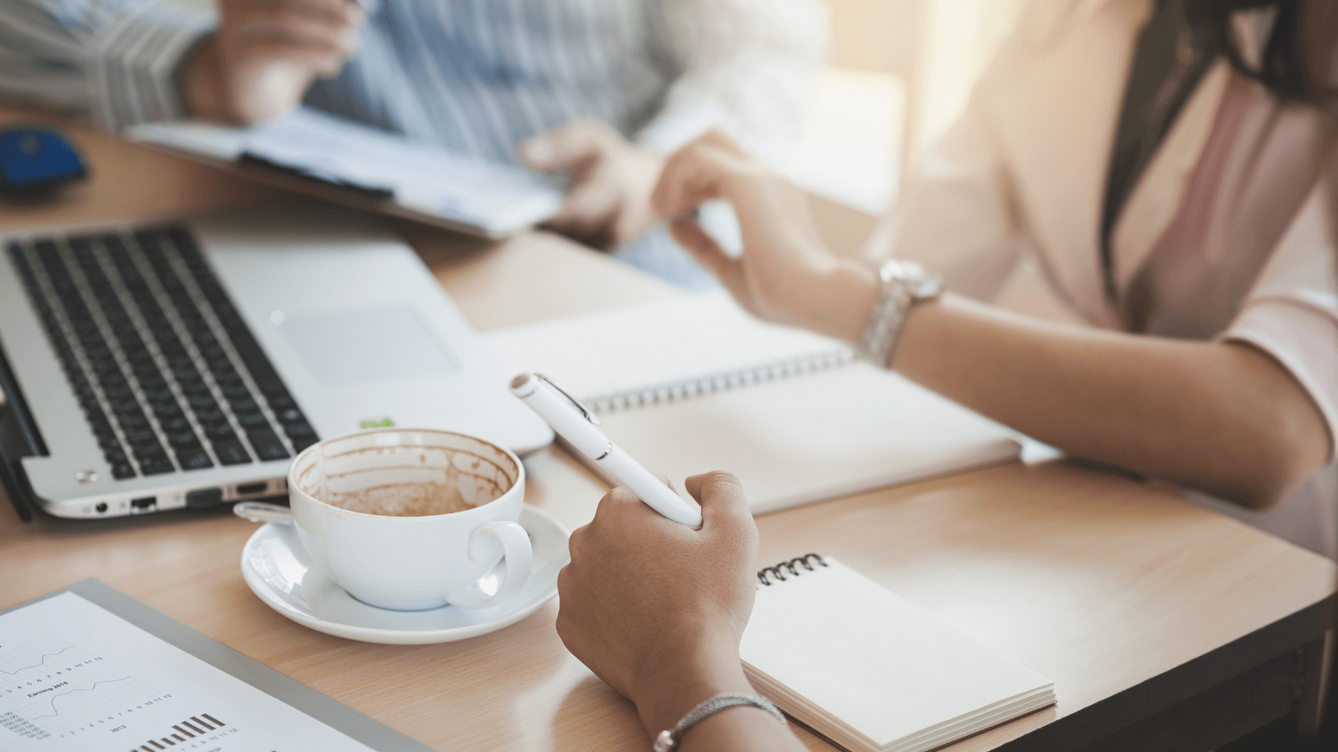 image of hands in a meeting taking notes