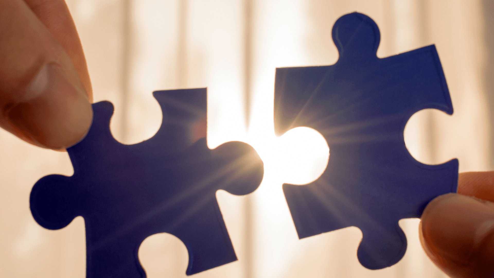 hands fitting two puzzle pieces together