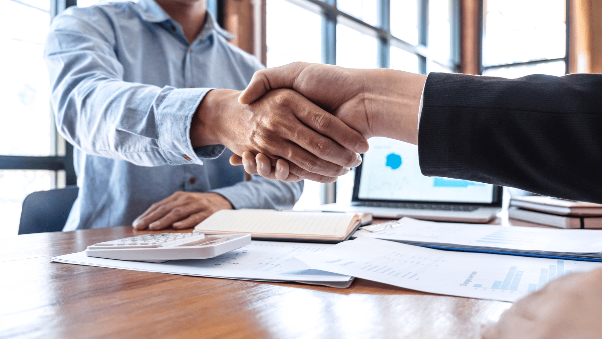 Two business professionals at a conference table shaking hands