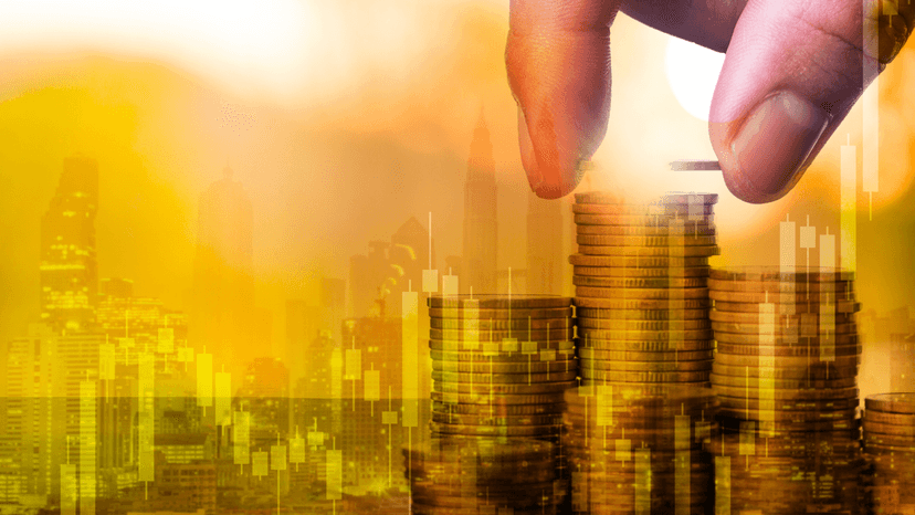 hand stacking money behind graphic of charts