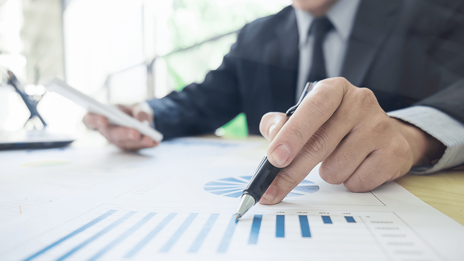 business man with pen and calculator looking at charts