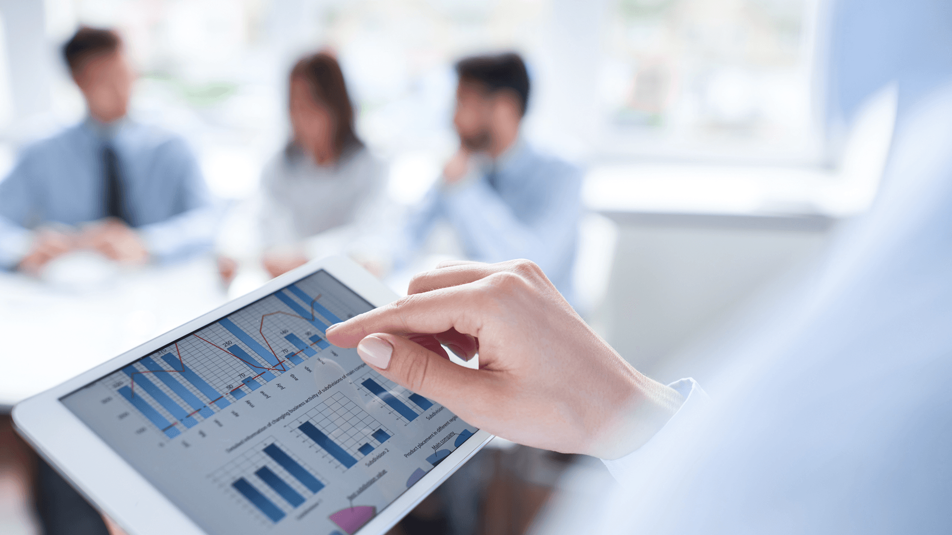 ipad with digital dashboard, meeting in the background