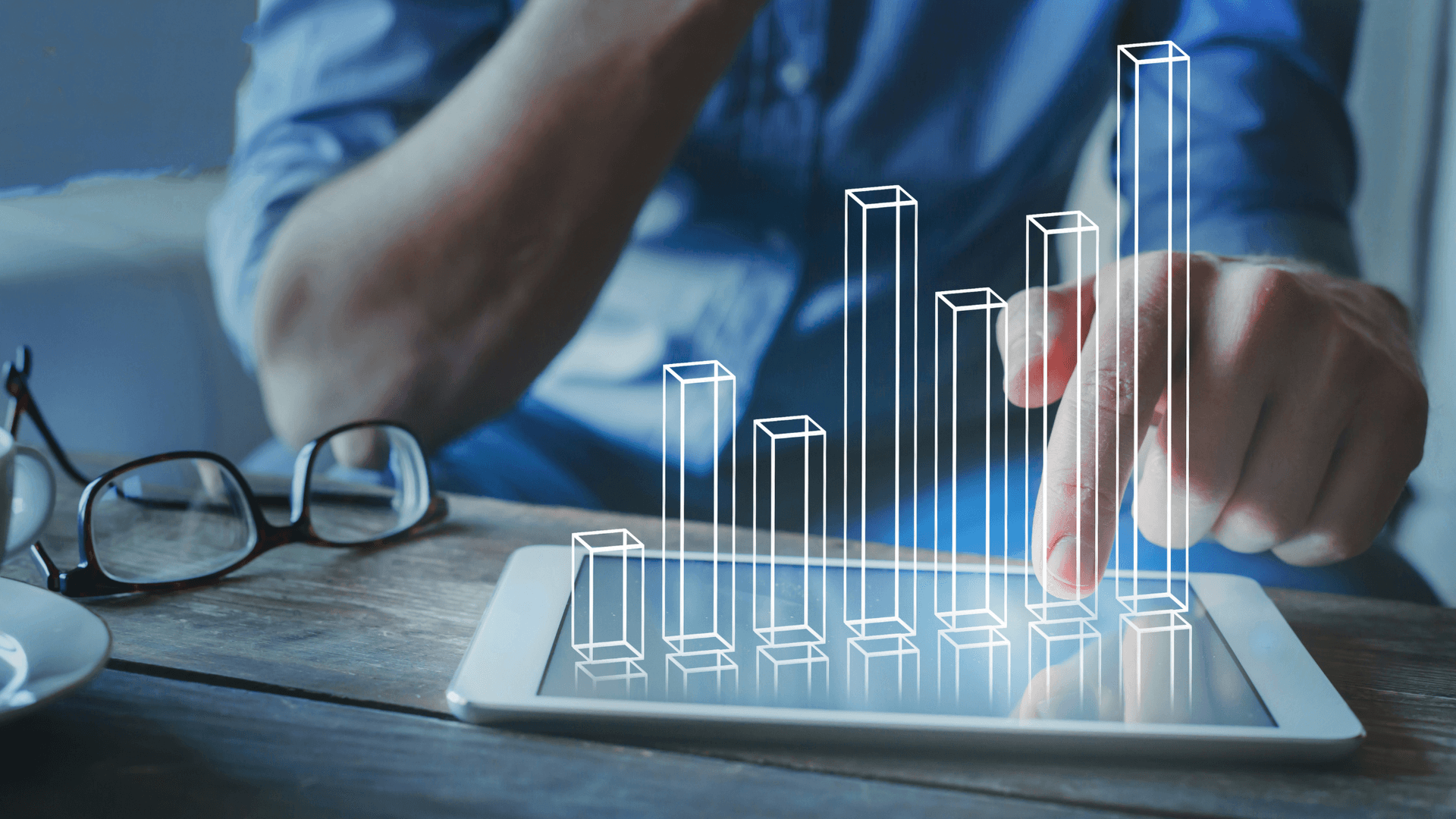 man looking at figures on ipad, table over lay popping out