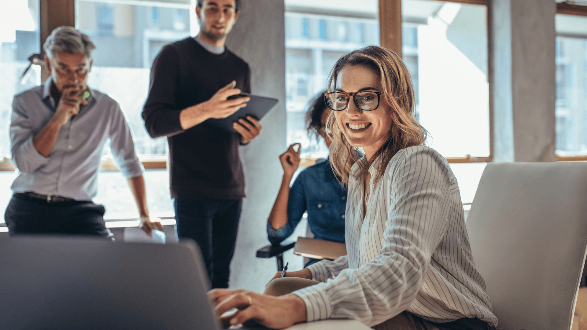professionals smiling and collaborating in a modern tech office