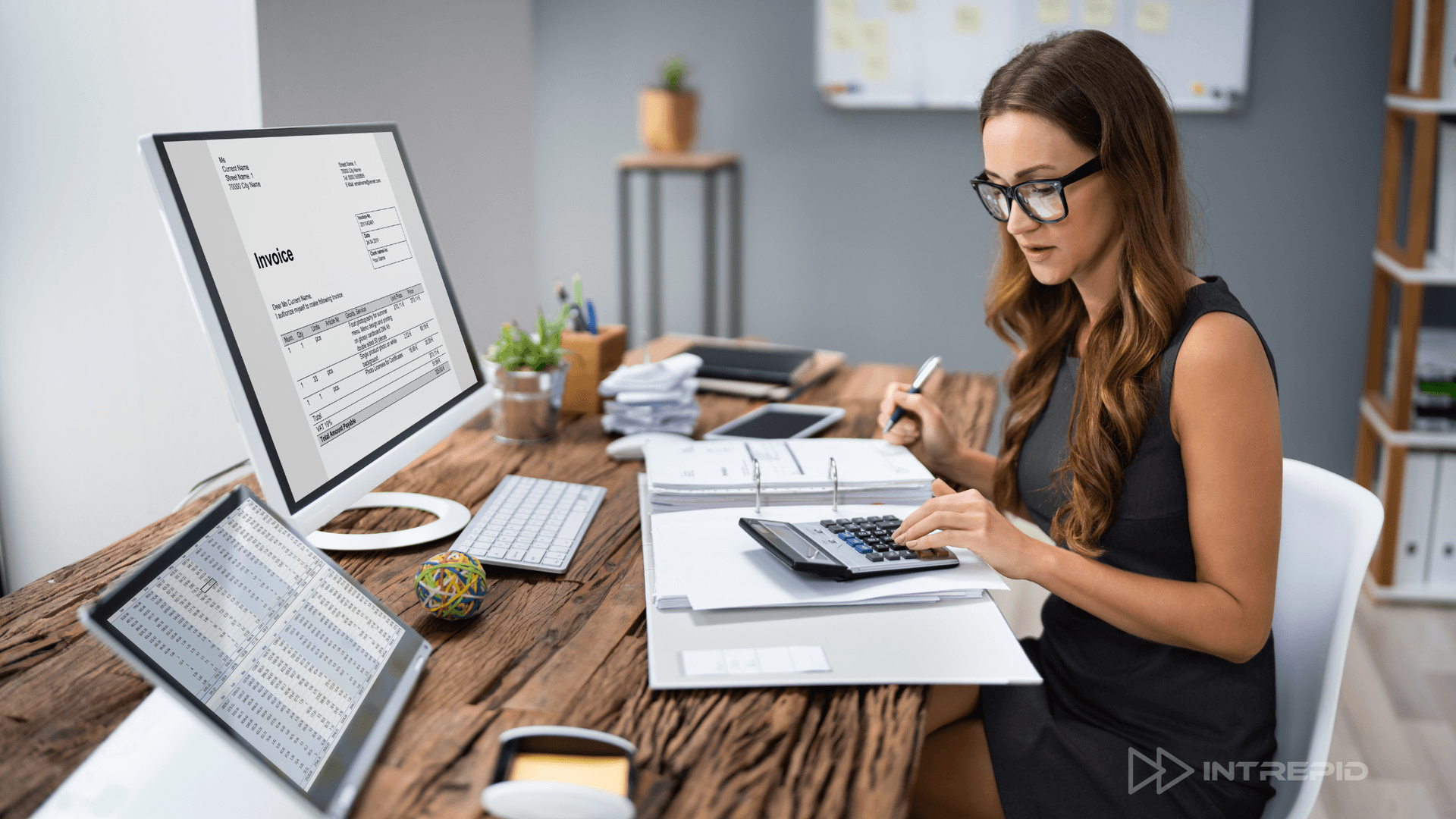 Businesswoman managing invoices and financials on screen and paper, representing flexible AR-backed funding solutions like Intrepid Finance's FlexAR.